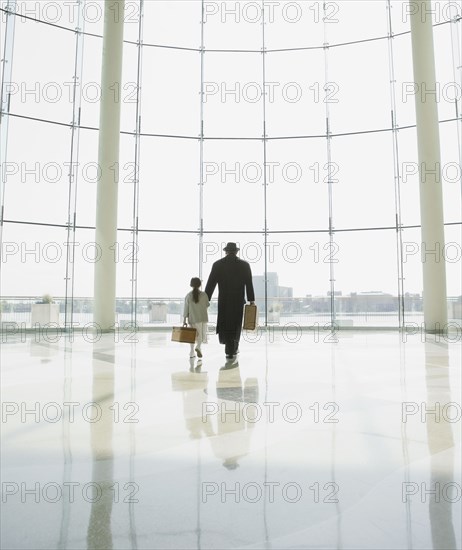 Hispanic father and daughter walking in airport