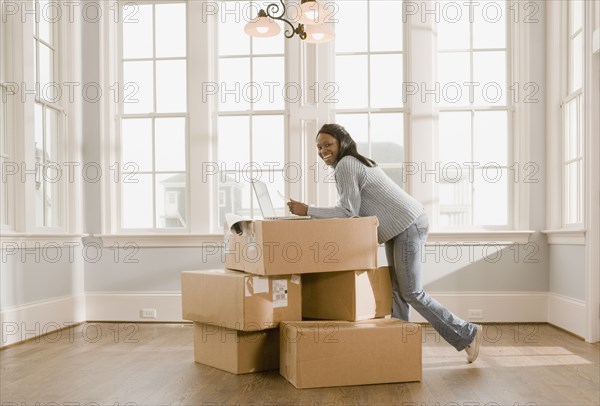 African woman using laptop on boxes