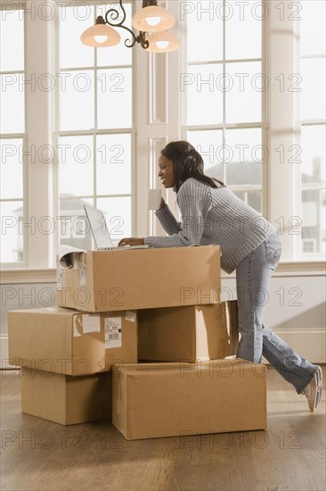 African woman using laptop on boxes