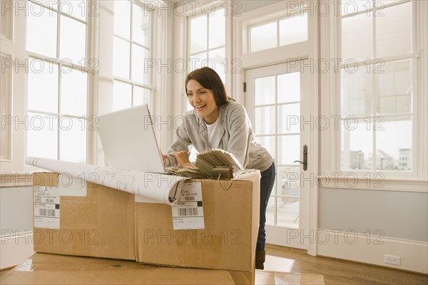 Hispanic woman using laptop on boxes