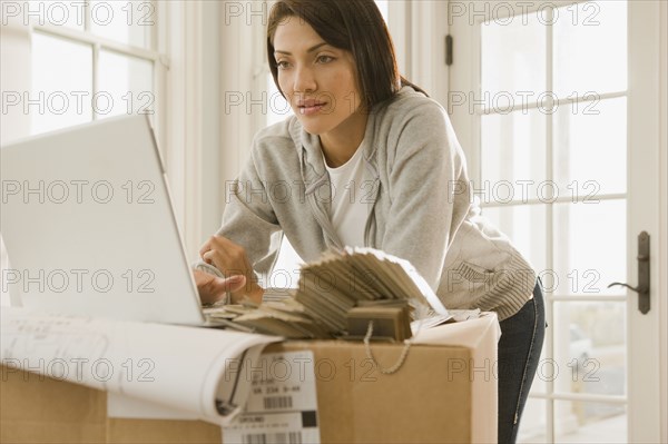 Hispanic woman using laptop on boxes