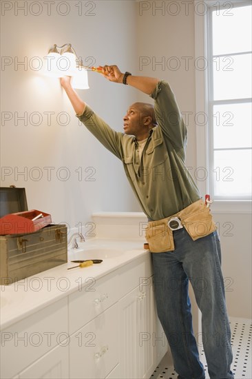 African man repairing light fixture