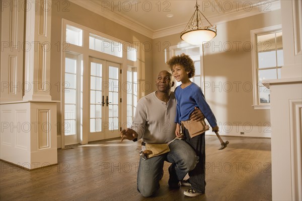 African father and son wearing tool belts