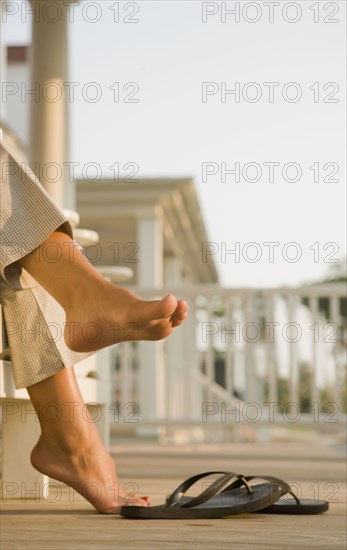 Mixed race woman barefoot near flipflops