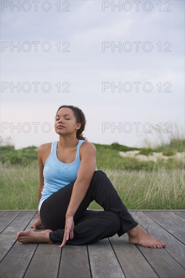 Barefoot mixed race woman stretching on deck