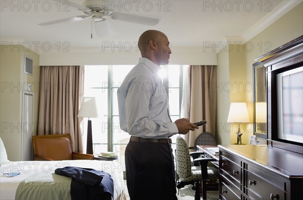 African businessman in hotel watching television