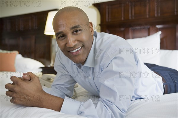 African businessman on hotel bed smiling