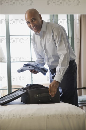 African businessman in hotel packing suitcase