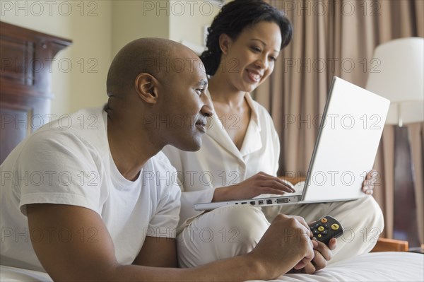 African couple in bed using laptop