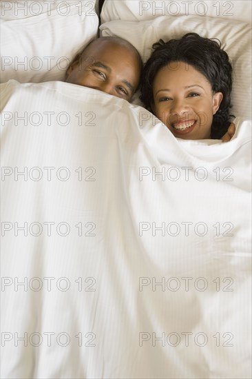 African couple in bed under blanket