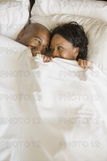 African couple in bed under blanket