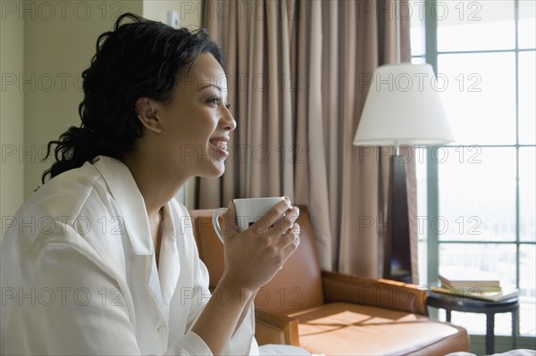 African woman drinking coffee in bedroom