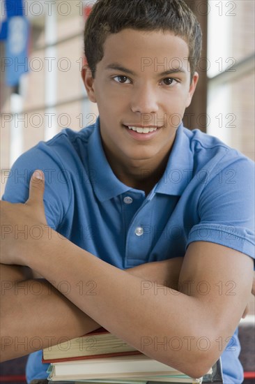 Mixed race teenager leaning on stack of books