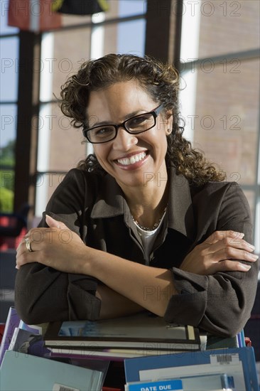 Hispanic librarian leaning on stack of books