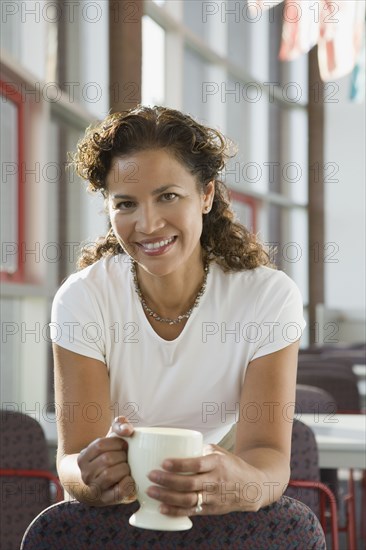 Hispanic businesswoman holding coffee cup