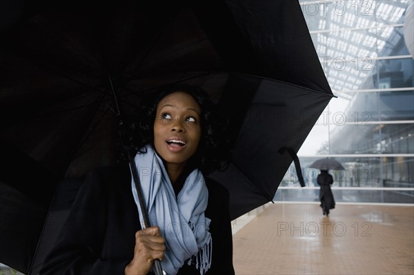African businesswoman holding umbrella in rain