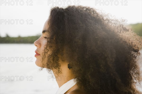 Profile of Hispanic woman standing near ocean