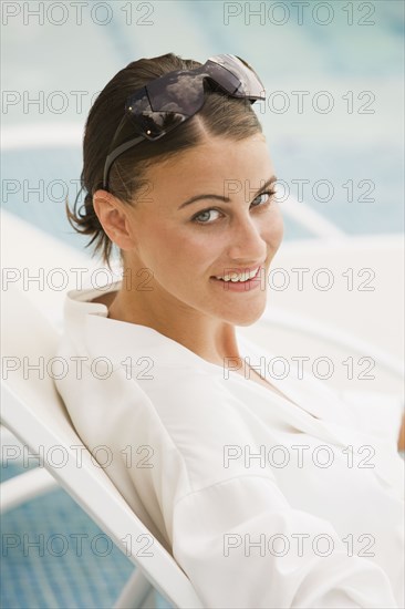 Mixed race woman in sunglasses sitting in lounge chair