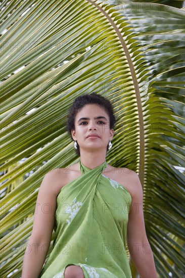 Hispanic woman in sarong near palm leaf