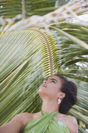 Hispanic woman in sarong near palm leaf