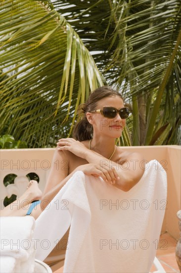 Mixed race woman sunbathing on lounge chair