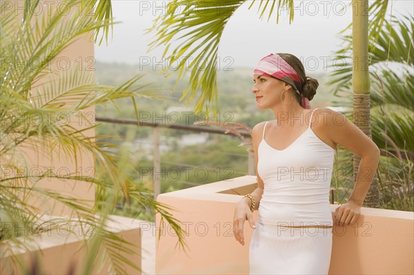 Mixed race woman leaning against balcony wall