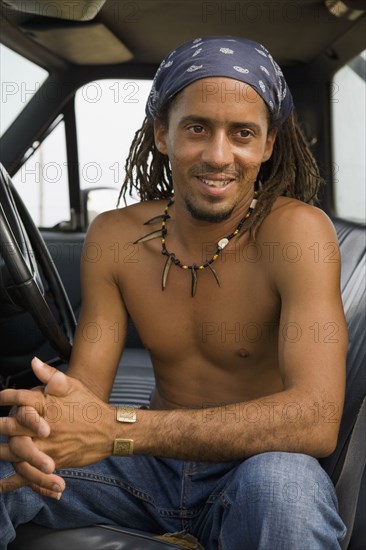 Bare chested Hispanic man sitting in cab of truck