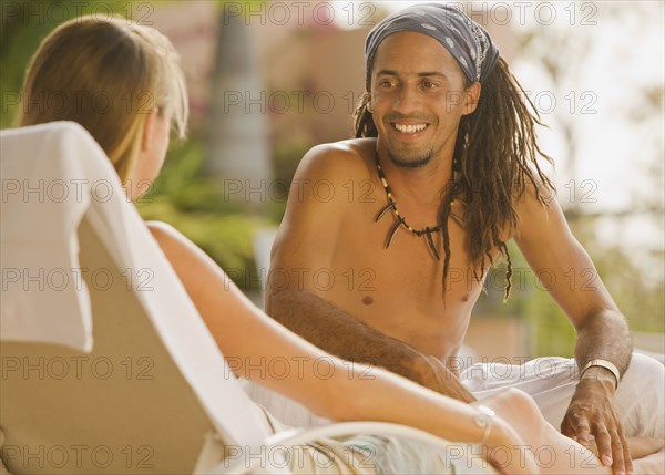 Hispanic man sitting on lounge chair talking to girlfriend