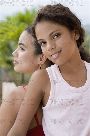 Hispanic girl back to back with young woman