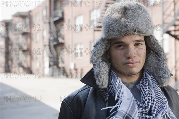 Mixed race man wearing fur hat on urban street