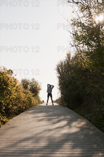 Mixed race woman stretching on boardwalk