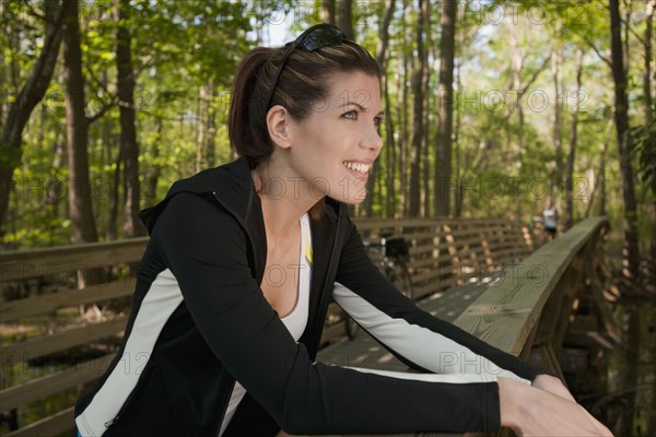 Mixed race woman leaning on bridge railing