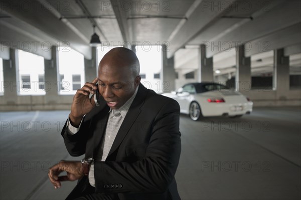 African businessman talking on cell phone in parking garage