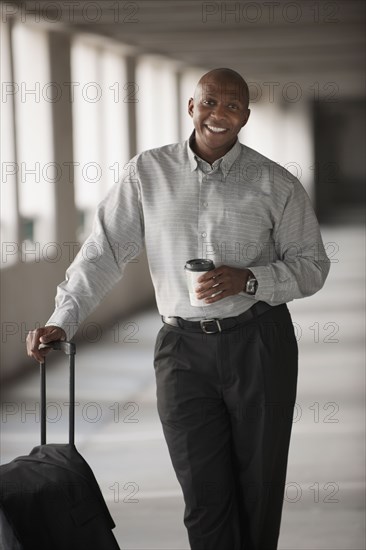 African businessman standing in parking garage with luggage