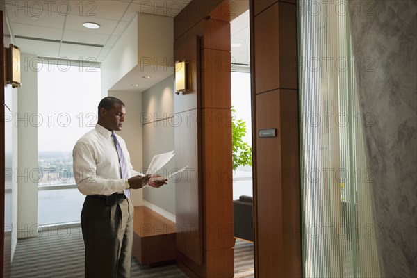 African American businessman holding paperwork in corridor