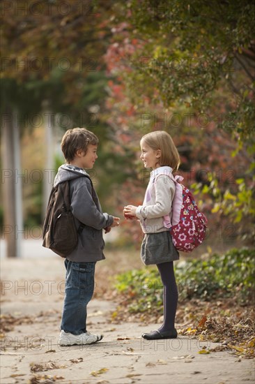 Mixed race brother and sister walking on sidewalk