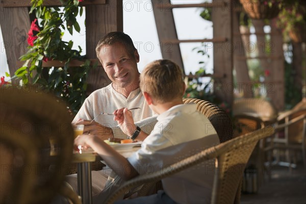 Caucasian father and son eating in restaurant