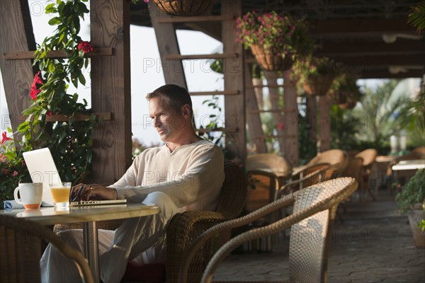 Caucasian man typing on laptop in restaurant