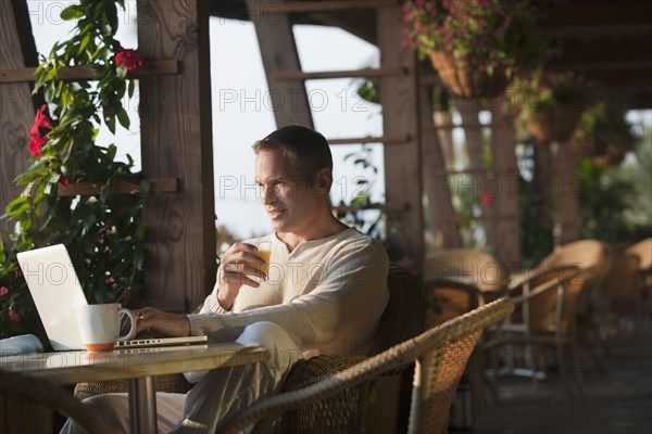 Caucasian man typing on laptop in restaurant