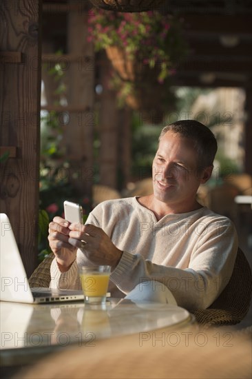 Caucasian man text messaging on cell phone in restaurant