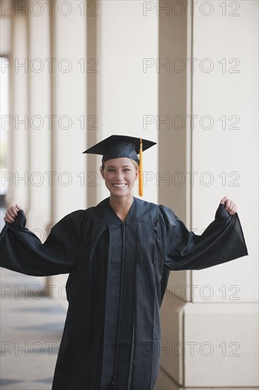 Caucasian graduate cheering in cap and gown