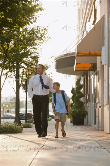 Caucasian businessman and son walking on city sidewalk