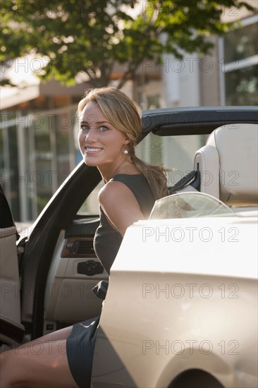 Caucasian woman getting out of convertible