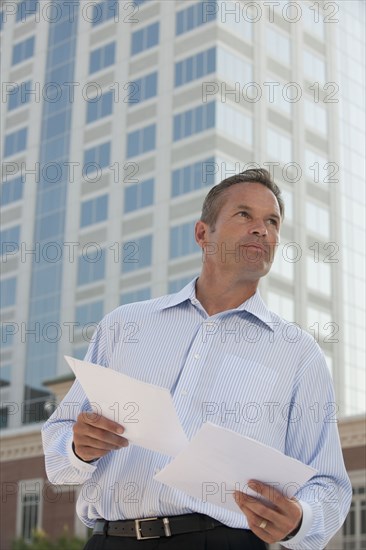 Caucasian businessman holding papers outdoors