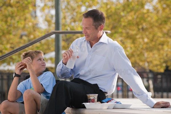 Caucasian father and son eating on steps