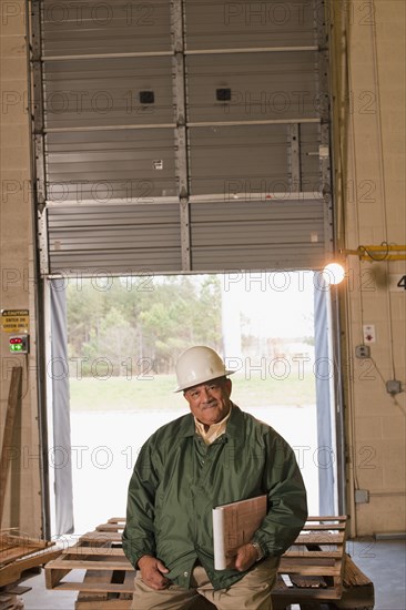 Mixed race man sitting on pallets in warehouse