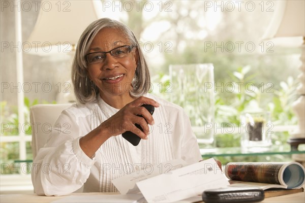 Black woman holding paper and cell phone