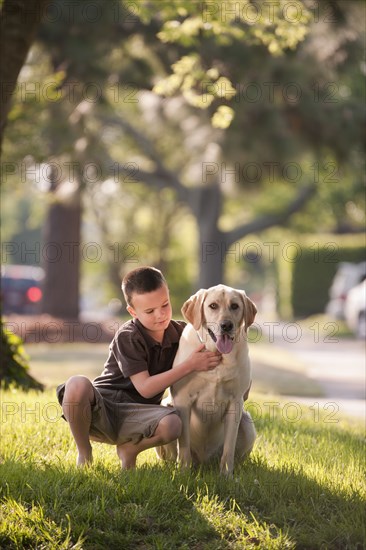 Caucasian boy petting dog in yard