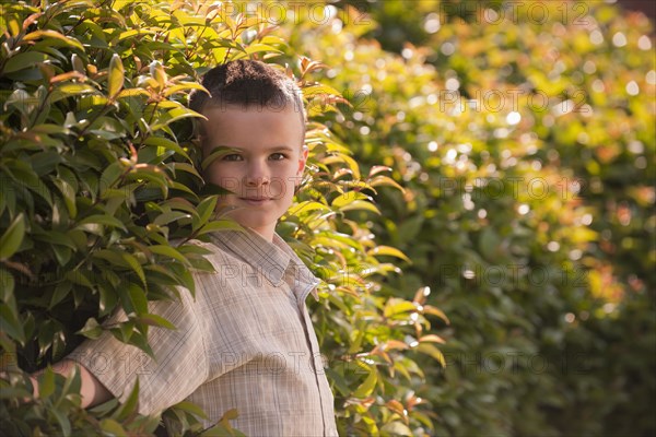 Caucasian boy standing near shrub