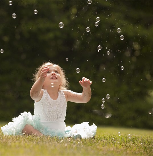 Caucasian girl watching floating bubbles